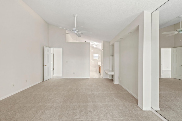 unfurnished room featuring light colored carpet, a textured ceiling, ceiling fan, and vaulted ceiling