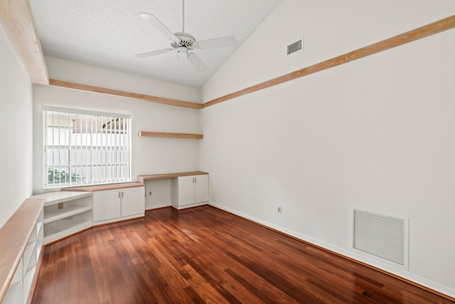 unfurnished office with dark wood-type flooring, a textured ceiling, high vaulted ceiling, ceiling fan, and built in desk