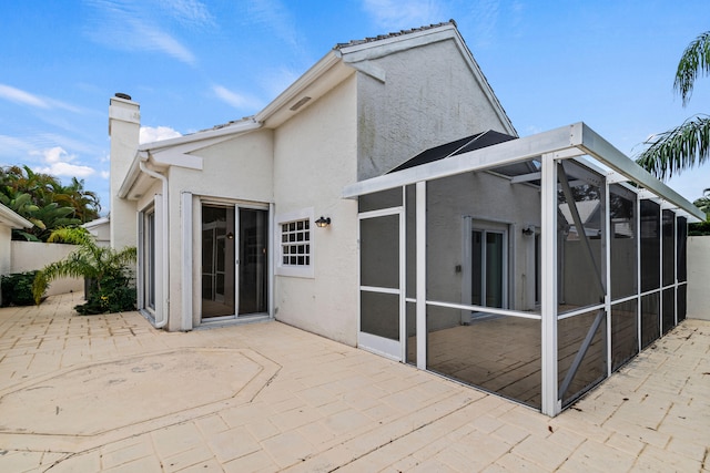 rear view of property featuring a patio and a sunroom