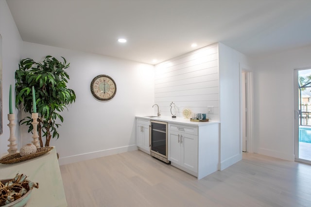 bar featuring white cabinetry, sink, beverage cooler, and light hardwood / wood-style floors