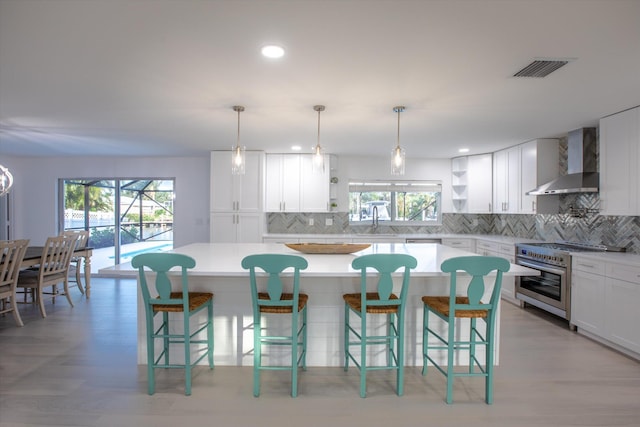 kitchen featuring white cabinetry, a kitchen island, high end stove, and wall chimney range hood