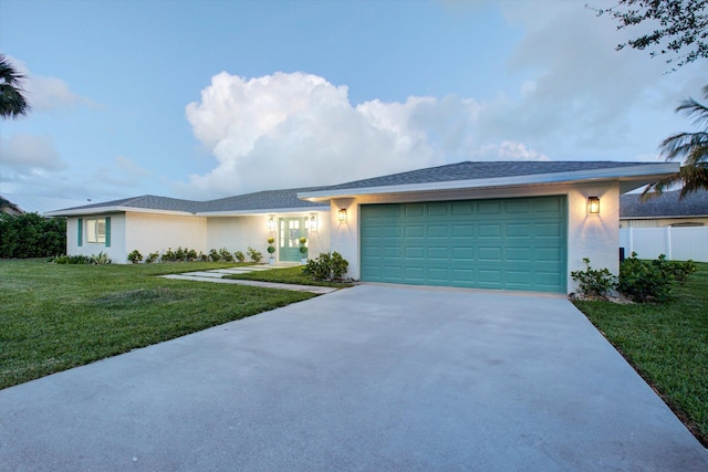 view of front facade with an attached garage, driveway, a front lawn, and stucco siding