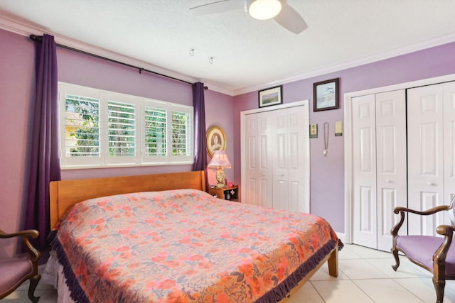 tiled bedroom with a textured ceiling, ceiling fan, crown molding, and multiple closets