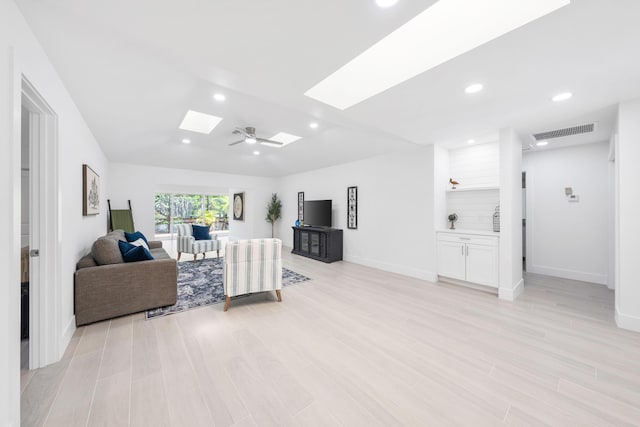 living room featuring light wood-type flooring, a skylight, and ceiling fan