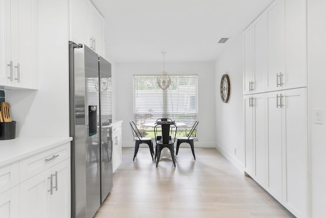 kitchen with white cabinetry, stainless steel fridge with ice dispenser, a notable chandelier, pendant lighting, and light hardwood / wood-style floors