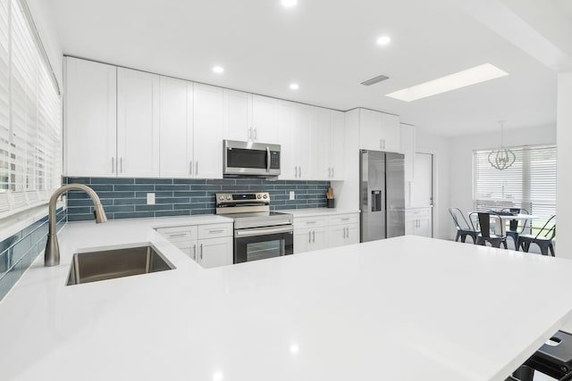 kitchen with white cabinetry, sink, pendant lighting, a breakfast bar area, and appliances with stainless steel finishes