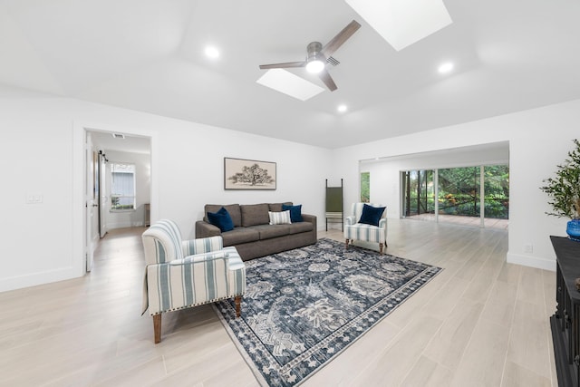 living room with a skylight, ceiling fan, and light hardwood / wood-style floors