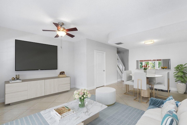 living room with light tile patterned floors, a textured ceiling, and ceiling fan