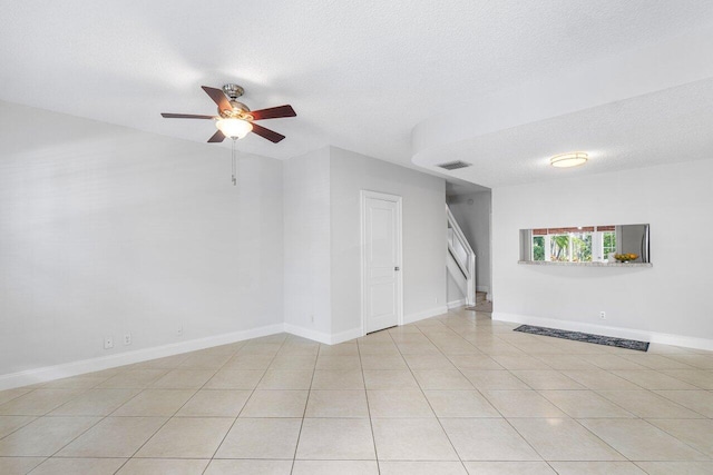 interior space featuring ceiling fan, light tile patterned floors, and a textured ceiling