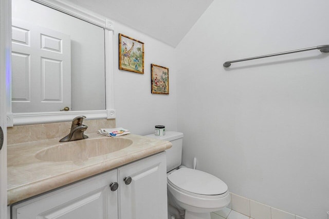 bathroom with toilet, vanity, lofted ceiling, and tile patterned flooring