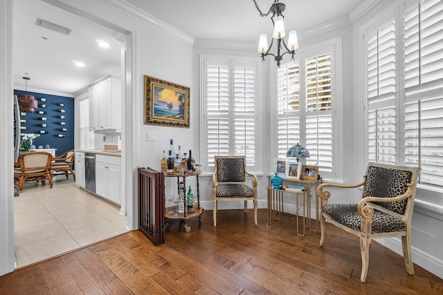 sitting room with ornamental molding, light hardwood / wood-style flooring, a notable chandelier, and a textured ceiling