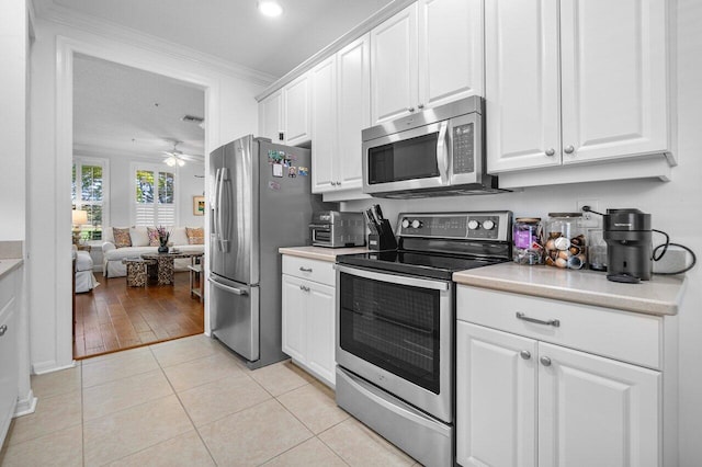 kitchen featuring light wood-type flooring, white cabinets, ornamental molding, and stainless steel appliances