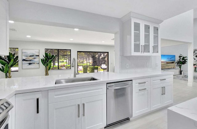 kitchen featuring dishwasher, white cabinets, sink, light stone countertops, and range