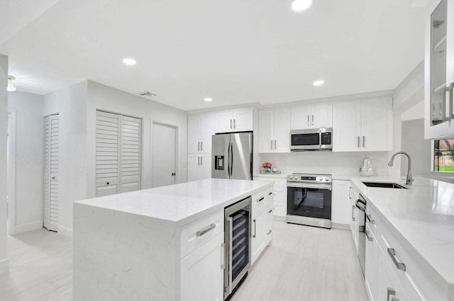 kitchen featuring white cabinetry, sink, a center island, wine cooler, and appliances with stainless steel finishes