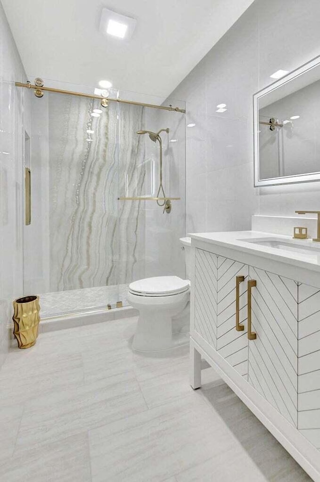 bathroom with tiled shower, vanity, and toilet