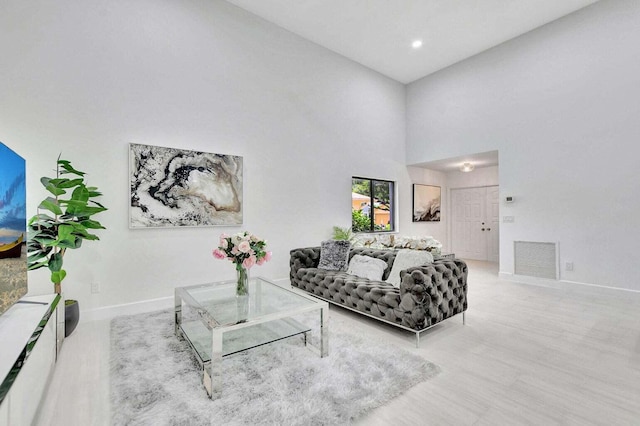 living room featuring light hardwood / wood-style flooring and a towering ceiling