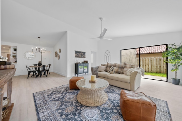 living room with ceiling fan with notable chandelier, lofted ceiling, and light hardwood / wood-style flooring