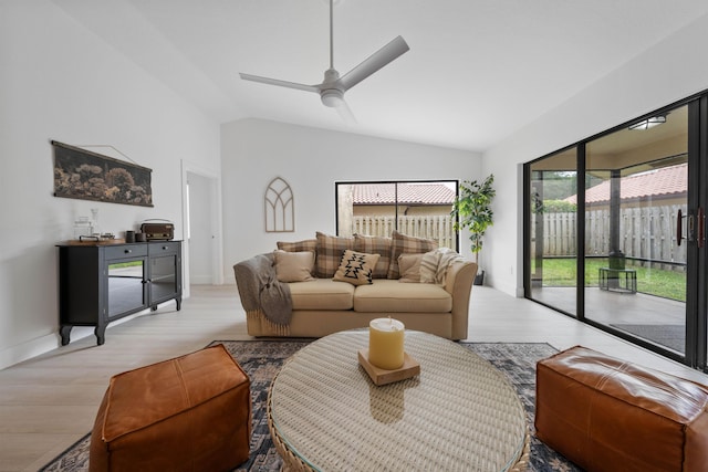 living room with light hardwood / wood-style flooring, ceiling fan with notable chandelier, and vaulted ceiling