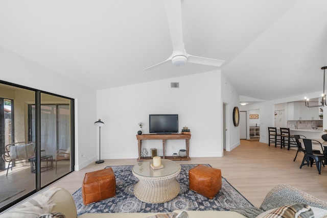 living room featuring light hardwood / wood-style floors, vaulted ceiling, and ceiling fan