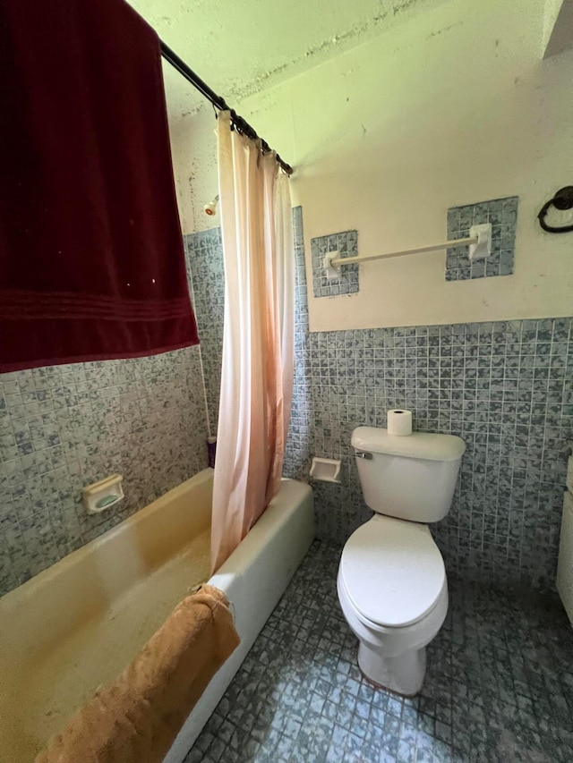 bathroom with toilet, tile walls, and shower / tub combo with curtain