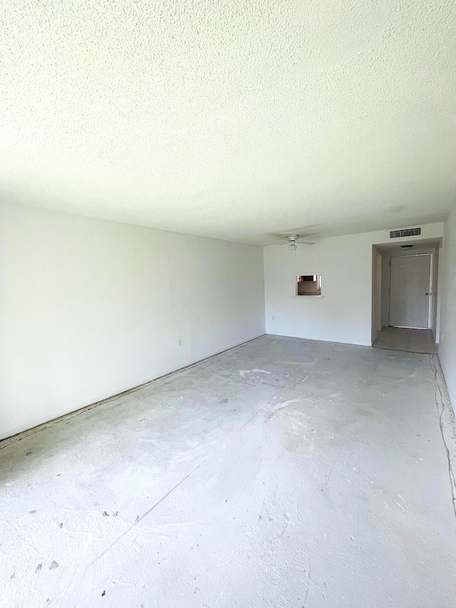 unfurnished room featuring a wall unit AC, concrete flooring, a textured ceiling, and ceiling fan