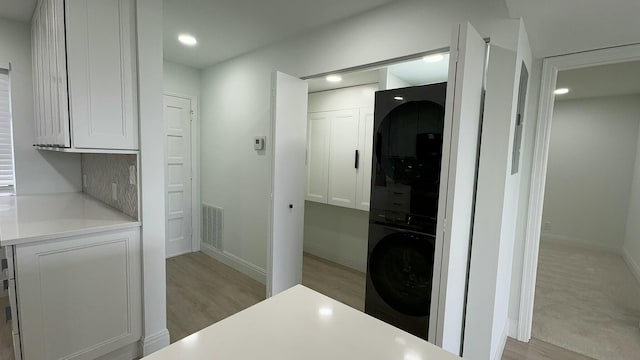 interior space with stacked washer and clothes dryer and light wood-type flooring