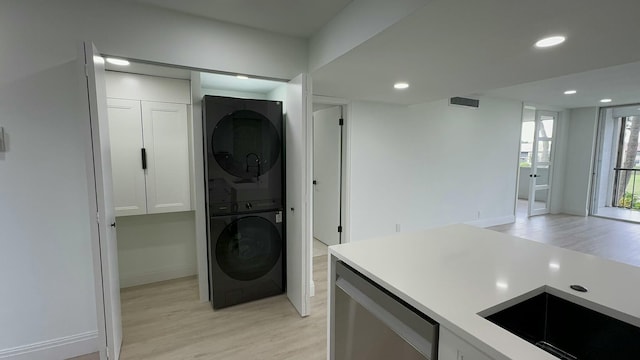 laundry room featuring light hardwood / wood-style floors, stacked washer and clothes dryer, and sink