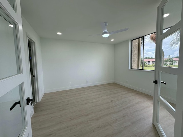 empty room with french doors, light wood-type flooring, and ceiling fan