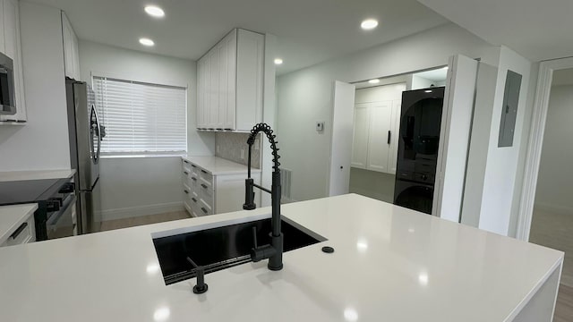 kitchen featuring stainless steel appliances, hardwood / wood-style floors, sink, electric panel, and white cabinetry