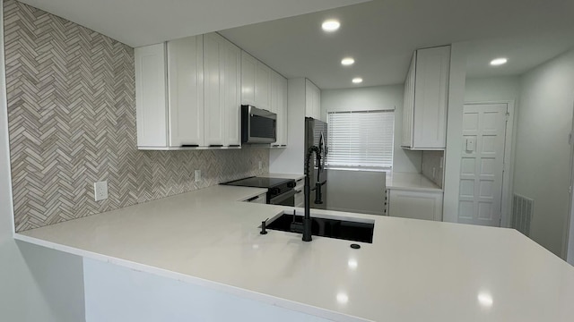 kitchen with kitchen peninsula, white cabinets, stainless steel appliances, and sink