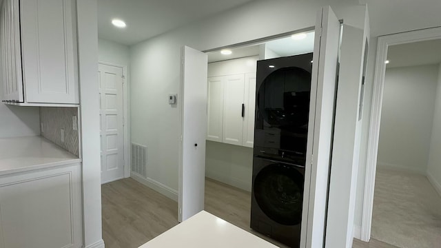 washroom featuring stacked washer / dryer and light wood-type flooring