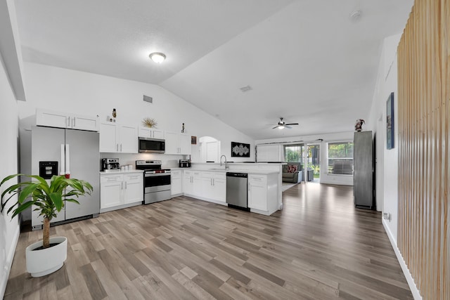 kitchen featuring sink, kitchen peninsula, appliances with stainless steel finishes, lofted ceiling, and white cabinets