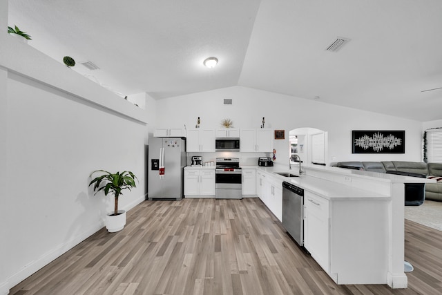 kitchen with stainless steel appliances, light wood-type flooring, white cabinetry, vaulted ceiling, and kitchen peninsula