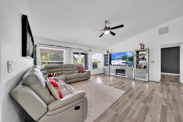 living room featuring light hardwood / wood-style flooring, vaulted ceiling, ceiling fan, and plenty of natural light