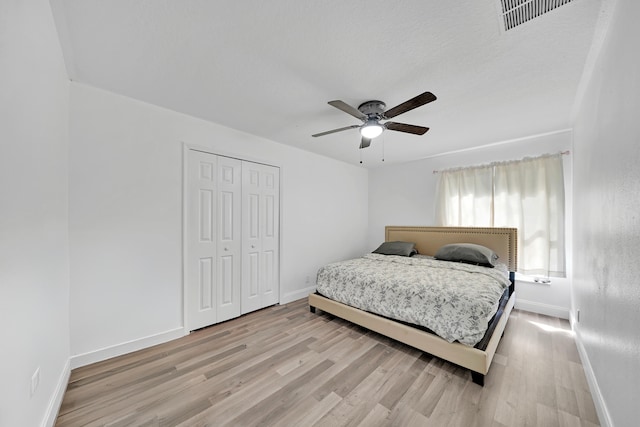 bedroom featuring a textured ceiling, light hardwood / wood-style flooring, ceiling fan, and a closet