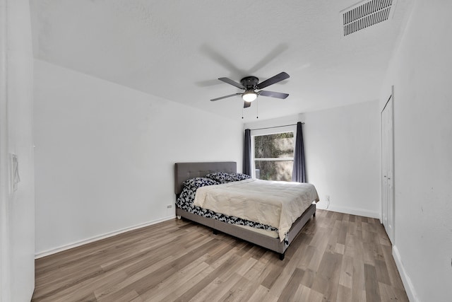 bedroom with light wood-type flooring, a textured ceiling, and ceiling fan