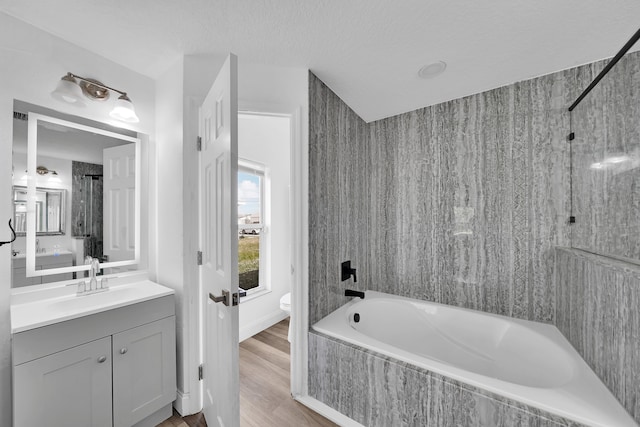 full bathroom featuring tiled shower / bath, a textured ceiling, wood-type flooring, vanity, and toilet