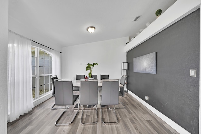 dining space with light hardwood / wood-style floors and vaulted ceiling