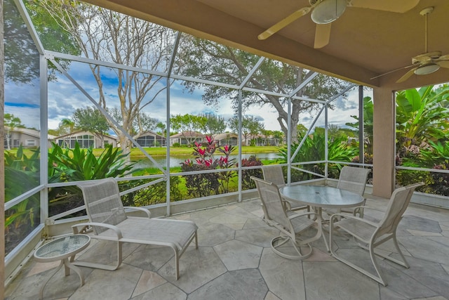 sunroom / solarium featuring a water view and ceiling fan