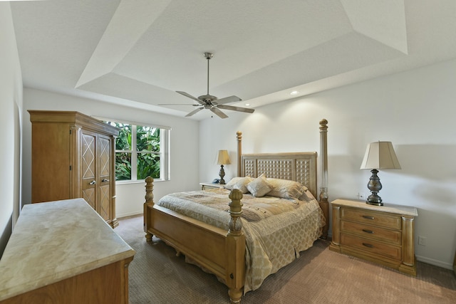 carpeted bedroom featuring a tray ceiling and ceiling fan