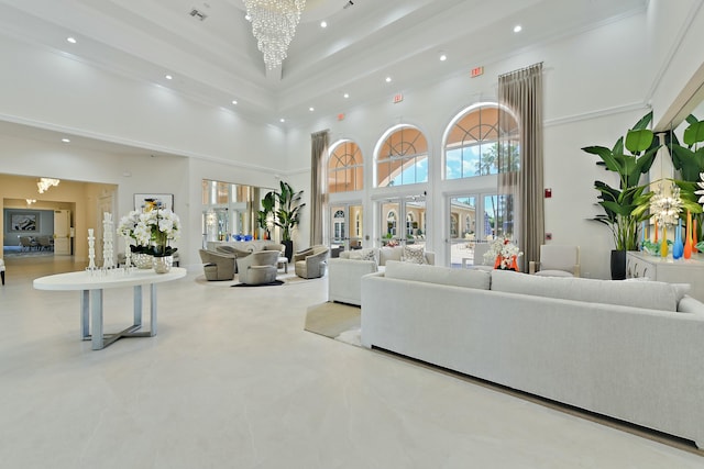 living room featuring a chandelier, a towering ceiling, and ornamental molding