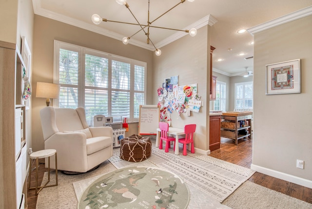 rec room featuring a chandelier, ornamental molding, a healthy amount of sunlight, and hardwood / wood-style flooring