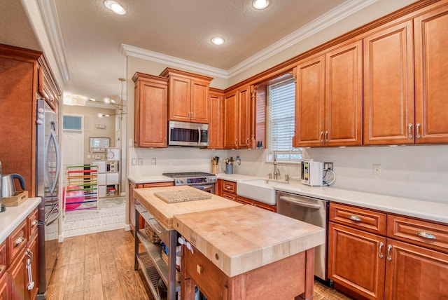 kitchen with stainless steel appliances, wood counters, crown molding, a textured ceiling, and light wood-type flooring