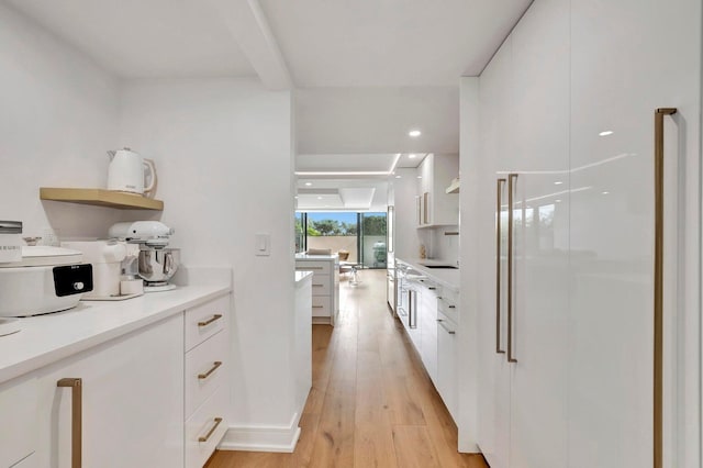 kitchen featuring white cabinetry, a wall of windows, and light hardwood / wood-style flooring