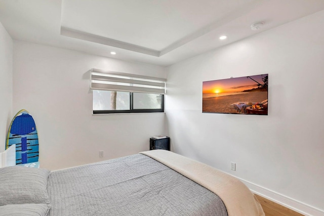 bedroom featuring a raised ceiling and hardwood / wood-style flooring