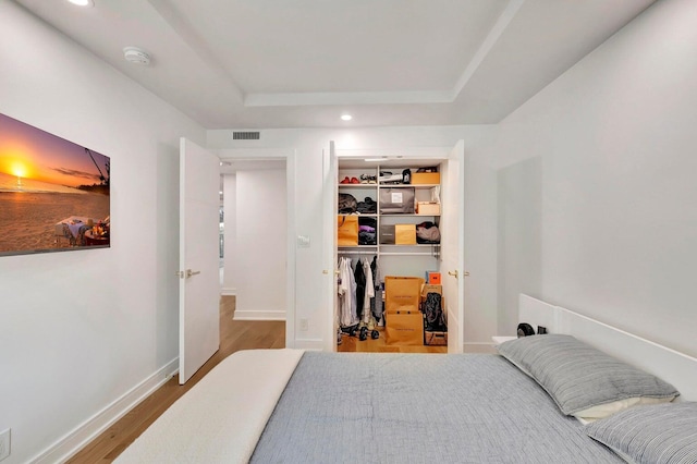 bedroom featuring a raised ceiling, a closet, and wood-type flooring