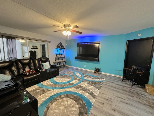 living room featuring ceiling fan, hardwood / wood-style flooring, and a textured ceiling