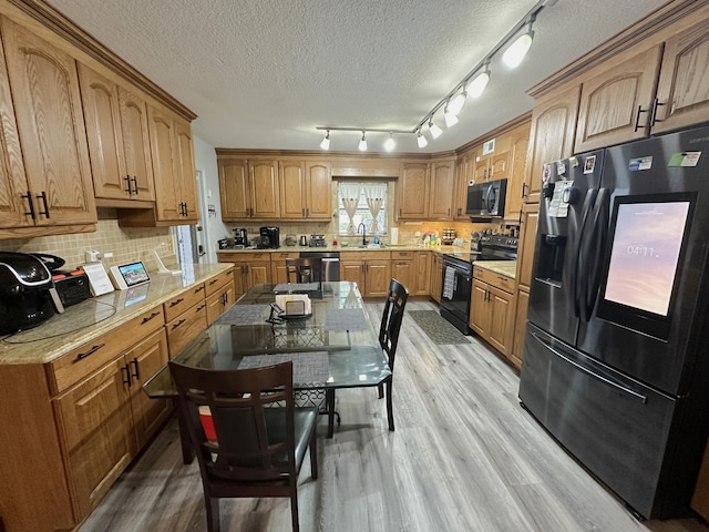 kitchen with sink, black appliances, light hardwood / wood-style flooring, and a textured ceiling