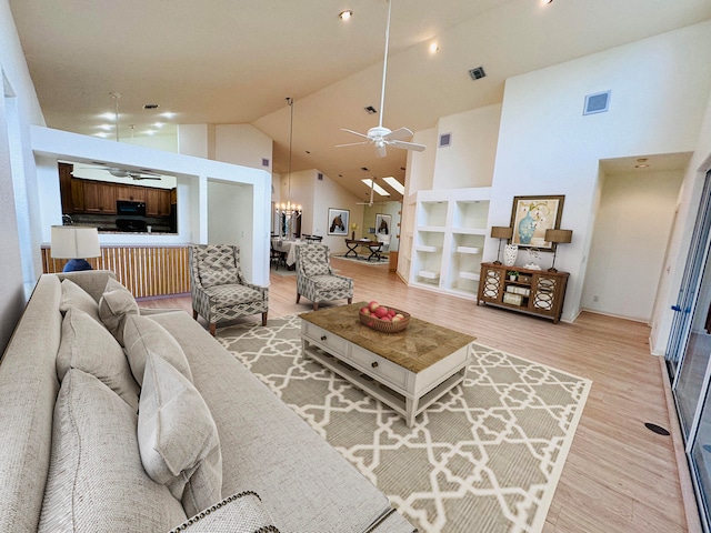 living room featuring hardwood / wood-style floors, ceiling fan with notable chandelier, and high vaulted ceiling