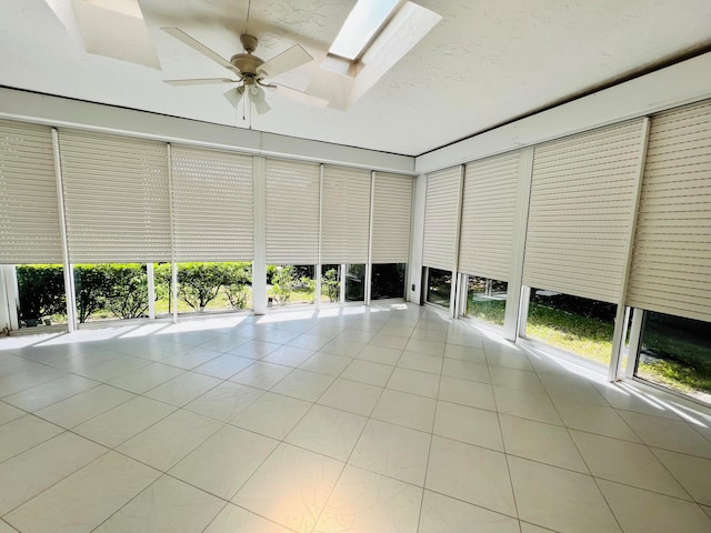 unfurnished sunroom with ceiling fan and a skylight